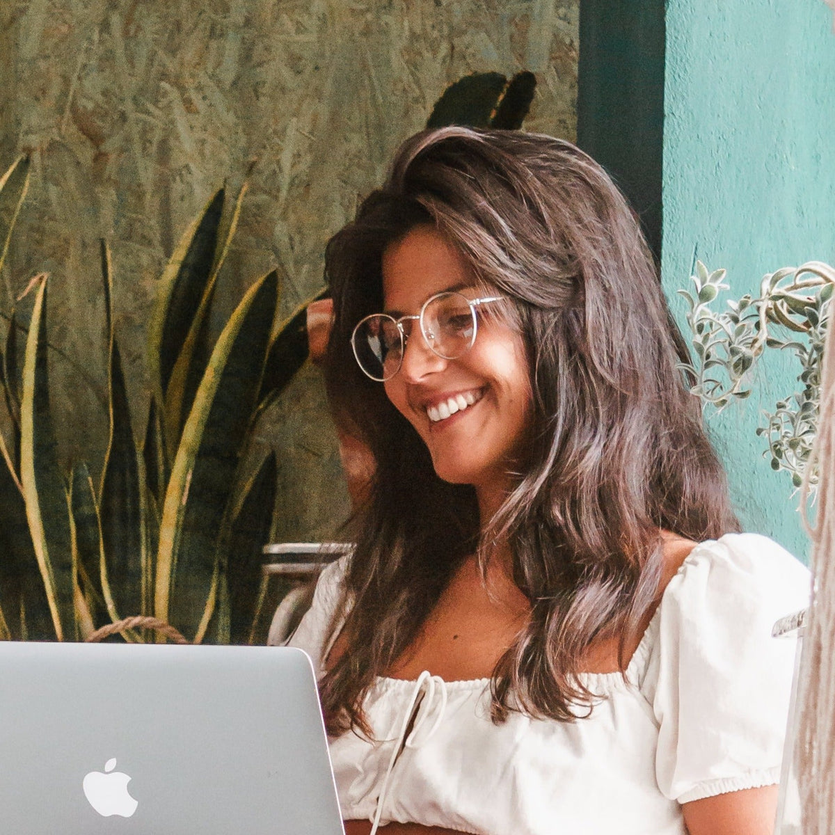 Mulher sorrindo em frente ao notebook usando óculos Floripa anti luz azul Fozoco