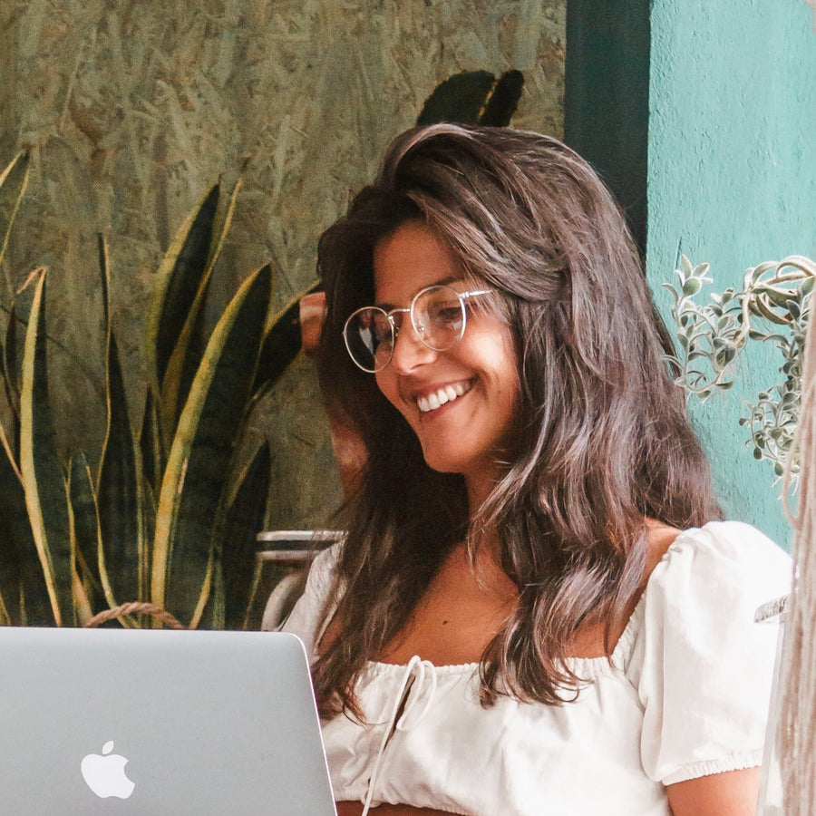 Mulher sorrindo em frente ao notebook usando óculos Floripa anti luz azul Fozoco